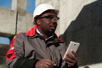 African american workman with smartphone at construction site