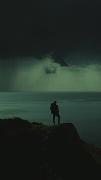 The traveler is standing on the mountain cliff on the night seascape background
