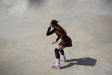 Roller blader female skating in a concrete pool. Aggressive inline skater chick riding in a...