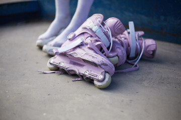 Female roller blader preparing for a ride in a skatepark. Young girl sitting in a urban park with a pair of modern purple aggressive in-line skates