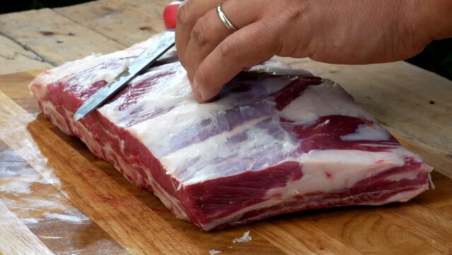 Griller cleans and checks rib rack of beef