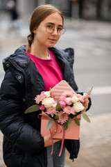 Bouquet of roses and chrysanthemums flowers in pink gift box in girl's hands
