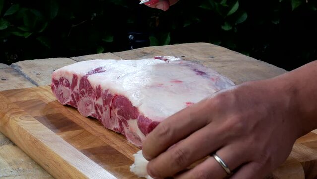 Griller cleans and checks rib rack of beef