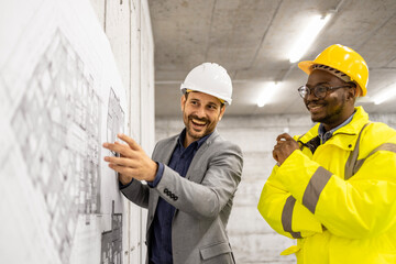 Construction engineer or architect presenting building plan and blueprint to the worker at the site.