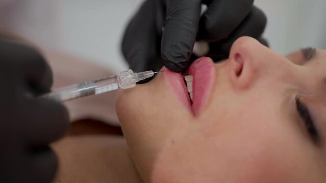 A cosmetologist performs a lip augmentation procedure in the salon.