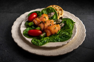 Asparagus spears wrapped in smoked salmon. Served with spinach and garnished with capers and chives.