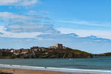 Tide coming in on golden sand with blue skies and coastline in distance