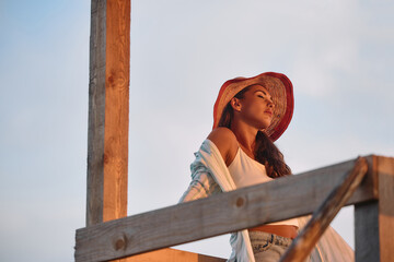 Woman with eyes closed enjoys in summer sunset.