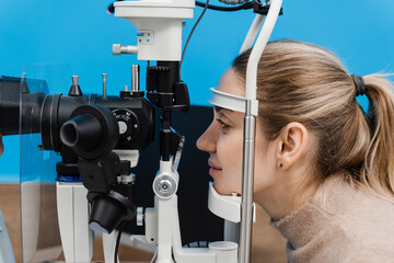 Ophthalmologist with slit lamp examines eyes and cornea of woman. Ophthalmologist illuminates eye...