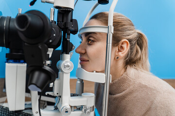 Ophthalmologist illuminates eye of child with light from slit lamp to diagnose the eyes and cornea....