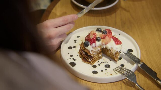 Close up of eating delicious cake with berries at the restaurant. Stock footage. Sharing cake dessert with a lover.