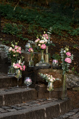 Pink and white flovers with crystal vases stands on stone stairs in the street