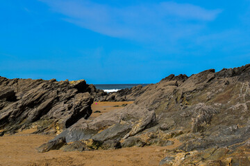 Fototapeta na wymiar rocks and rockpools golden sand at the beach in spring summer with blue skies