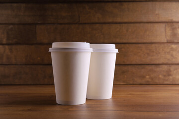 a paper cup of coffee on a wooden table with coffee beans