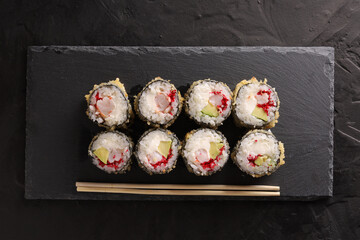 Sushi and rolls set on a black plate and black background