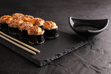 Sushi and rolls set on a black plate and black background
