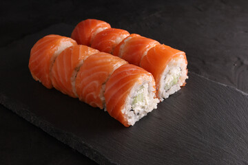 Sushi and rolls set on a black plate and black background