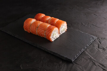 Sushi and rolls set on a black plate and black background