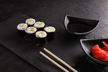 Sushi and rolls set on a black plate and black background