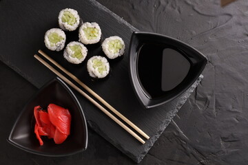 Sushi and rolls set on a black plate and black background