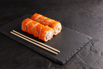 Sushi and rolls set on a black plate and black background