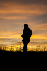 Beautiful woman drinking coffee in a field with sunset in the background