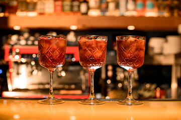 Red cocktails with ice cubes in glasses on the bar counter in the bar
