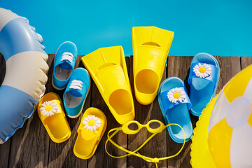 Beach flip-flops and sunglasses on wooden planks near swimming pool