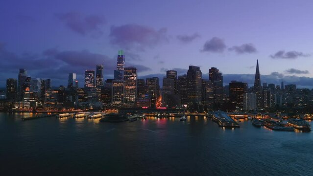 Amazing Arial view Of The San Francisco City Skyline and Ferry Terminal during gorgeous sunset time. Purple sky and clouds behind the nighttime skyscrapers. SF, California. USA