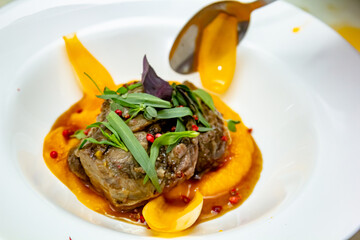 A deliciously appetizing pumpkin puree with chunks of beef meat with spices and herbs in a green plate on a dark stone table. A hearty lunch in a restaurant. Meat with vegetables in the oven
