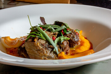 A deliciously appetizing pumpkin puree with chunks of beef meat with spices and herbs in a green plate on a dark stone table. A hearty lunch in a restaurant. Meat with vegetables in the oven