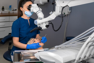 Professional dentist examines a patient with a microscope in a dental office. Modern dental office with new equipment.