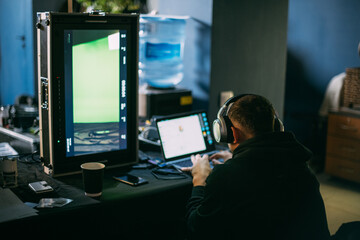 Editing director behind monitors on the set. A video editor edits video online while filming for a playback.