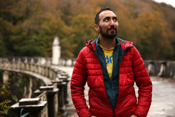 Trekking lover, adventurer bearded Caucasian man posing in front of a green blurry background in the forest. Copy space for text, advertising, message