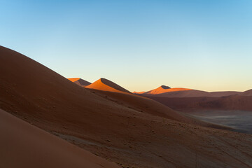 Fototapeta na wymiar Majestätische Schönheit: Rote Sanddünen Afrikas mit blauem Himmel - Die kraftvolle Pracht der Natur
