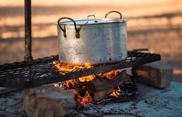 Cooking a Hearty Meal in an Old Big Pot Over an Open Fire Amidst the Serenity of Outdoor Camping Adventures