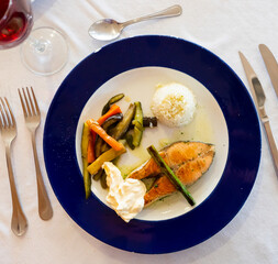 Appetizing salmon fillet baked with pieces of vegetables and served with rice on plate