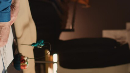 Vertical video Experienced tailor choosing model to make clothes, looking at modern sketches in atelier. Couturier crafting custom made fashion items with textile industry tools and skill. Handheld