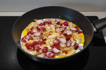 Pasta with egg and radish in a pan.