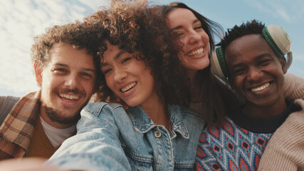 Happy smiling friends make a video call from a mobile phone. Four students wave their hands in greeting