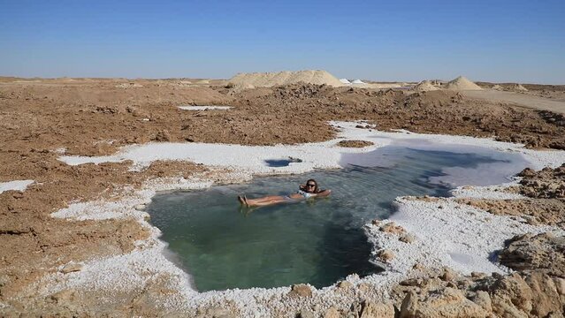 A beautiful young woman swims in Salt Plains and Lakes in Siwa Oasis, Egypt