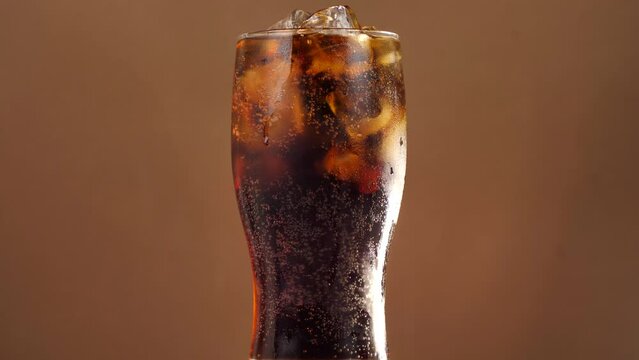 rotating glass of cola with ice cubes . Cola with ice and bubbles in a glass. coca cola