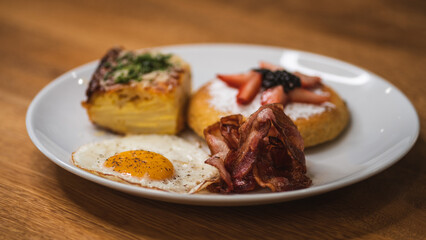 tasty waffle breakfast with fruits, bacon, egg and potato soufflé