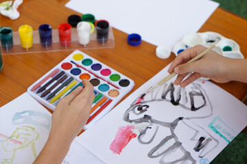 Closeup student is studying art subject, painting, art activity, enjoy and concentrate on favorite activity with many colors. Concept, Education. Learning by doing, enhance kid's imagination. 