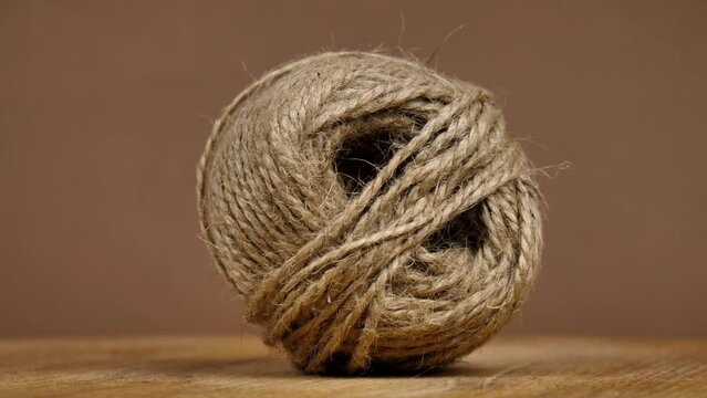 A skein of hemp twine with a braided texture rotate on a brown background