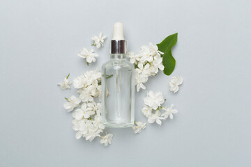 Face serum with flowers on color background, top view