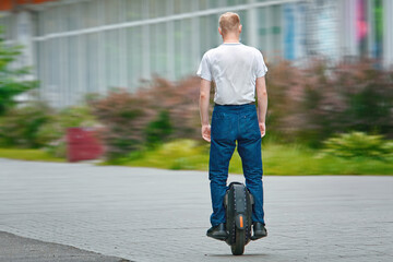 Man riding on monowheel. Man commuting to work, riding electric unicycle (EUC). Man driving electric mono wheel, ecological transportation in city..