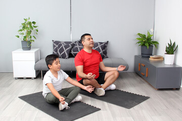 Latino father and son practice yoga, a traditional spiritual, physical and mental discipline in...