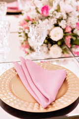 a sousplat on top of a glass table, with a pink napkin