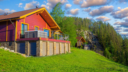 Wooden cottage with panoramic windows.  Private house with a green lawn.  Cottage in sunny weather.